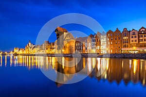 Historic port crane and ship over Motlawa river in Gdansk at night