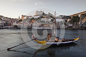 Historic port wine boat in front of the city Porto with river Douro during sunset, Portugal