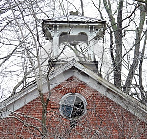 Historic red brick building with round window and wood bell cupola tower