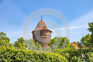 historic red brick tower rising above trees against a blue sky