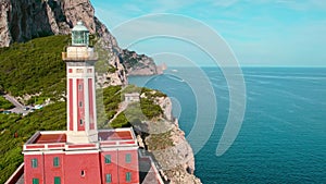 Historic red lighthouse on Capri coastline overlooking the vast Tyrrhenian Sea. Faro di Punta Carena on the edge of