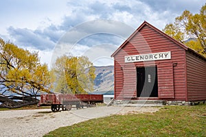 Historic red railway shed at Glenorchy with mountain and golden fall colors foliage background