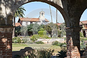 Historic Spanish Style Mission Church building in California framed in an arch during the day