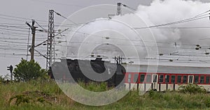 Historic steam locomotive with passenger wagons on rail tracks