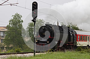 Historic steam locomotive with passenger wagons on rail tracks