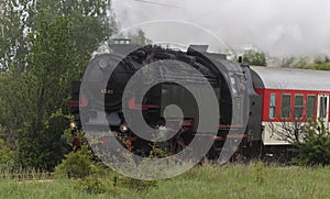 Historic steam locomotive with passenger wagons on rail tracks