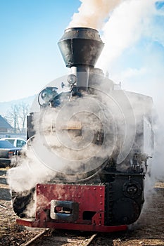 Historic steam train passing an old Romanian village