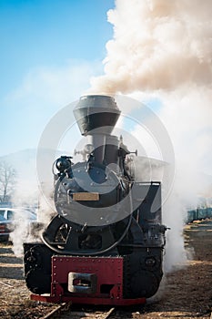 Historic steam train passing an old Romanian village