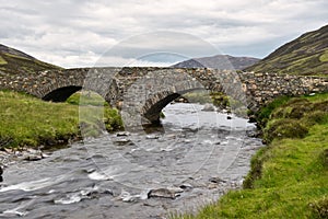 Historic stone bridge across a small river in the Scottish Highlands photo