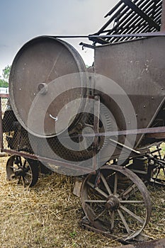 Historic straw press following a threshing machine in operation. The wheel turns and shows motion blur