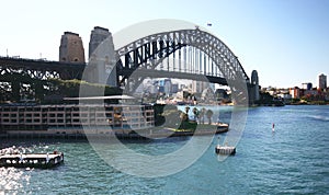 Historic Sydney Harbor Bridge with Park Hyatt Hotel on waterfront. Heritage steel truss arch bridge spanning over water