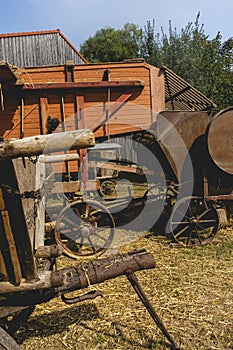 Historic threshing machine with subsequent straw press in operation. In the foreground is a historic wooden cart for the mown