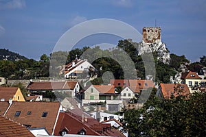 A historic town with red roofs under a hill with a round stone tower