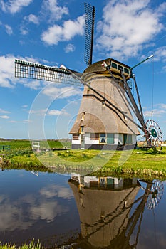 A historic windmill with reflection on the water.