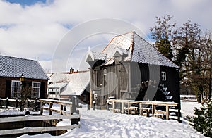 Historic wooden building, water mill in dutch rural landscape with snow. Winter scenic locations architecture. Tourism travel dest