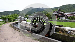 Historic wooden water wheel by irrigation canal and rice field in rural Japan