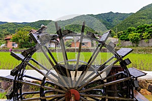 Historic wooden water wheel by rice field in Japanese countryside