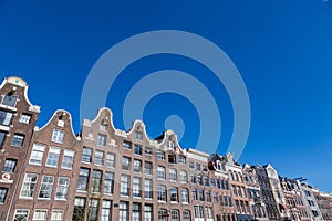 Historical Amsterdam canal houses on a blue sky.