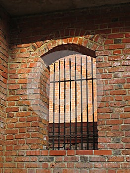 Historical Arched Window with Iron Bars on Red Brick Wall