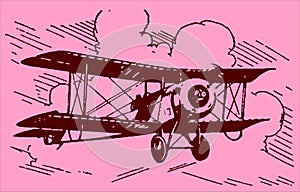 Historical biplane aircraft flying under a cloudy pink sky at sundown