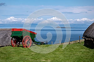 A historical cart in the Skye museum of island life with ancient houses and sea in the background in Northern Scotland