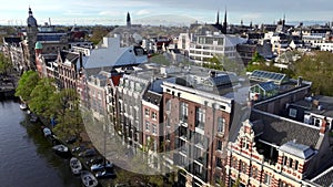 Historical Center of Amsterdam, Netherlands. Aerial Drone Shot of Traditional Dutch houses on narrow street and channel.