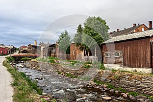 Historical charm of Roros captured by rustic wooden houses along Glomma River and a serene flowing stream