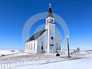 A historical country church sits atop a hill in the prairie
