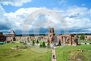 Historical fortress ruins on green meadow against blue sky