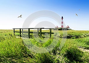 The historical lighthouse Westerhever and a small bridge in the salt meadows, Germany