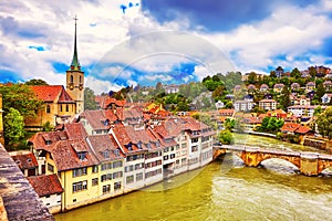 Historical Old Town of Bern city, tiled roofs, bridges over Aare river and church tower on dramatic sunset, Switzerland