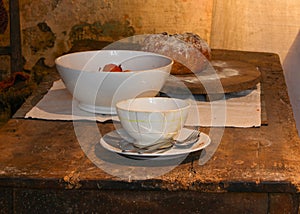 historical reconstruction of an ancient table set with bowl and bread in the old rural kitchen of the farm