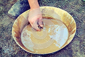 Historical reconstruction of prospector by hand, retro. A man stands next to a tray for washing gold sand. Washing of gold in tray