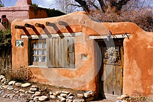 Historical Santa Fe adobe house with old styled wood beams and adobe stucco.