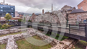 Historical Taslihan ruins timelapse with the old watch tower and minaret of Gazi Husrev mosque photo