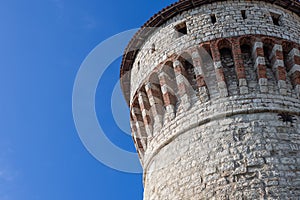 The historical Torre dei Prigionieri in Brescia castle, captured in bright daylight, showcases its intricate brickwork