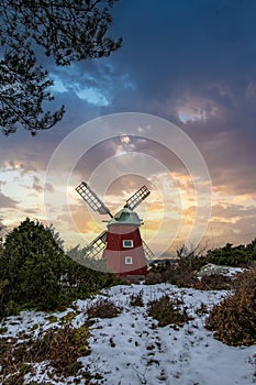 historical windmill made of red wood in a winter landscape.Stenungsund in Sweden photo