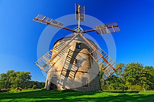 Historical windmill Svetlik near town Krasna Lipa, Czech Republic. Beautiful landscape with windmill and dark blue sky. Green tree