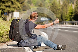 Hitchhiker man traveler sitting on the roadside