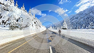 Hitchhiker man walking on snowy roads in winter season