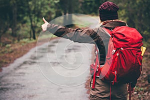 Hitchhiker with red backpack alone on the road