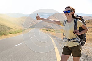 Hitchhiker traveler woman on the road in sunset. Girl traveler hiker on the road. Summer vacation. Freedom.