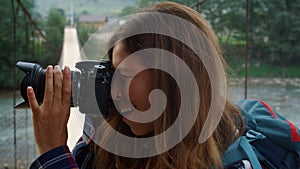 Hitchhiker woman taking photos using digital camera on nature forest landscape.