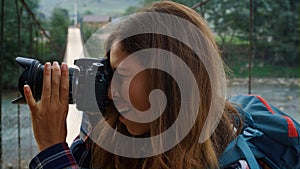 Hitchhiker woman taking photos using digital camera on nature forest landscape.