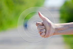 Hitchhikers sign thumb up at road background