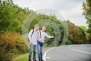 Hitchhiking gesture. Begin great adventure in your life with hitchhiking. Company friends travelers hitchhiking at road
