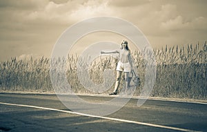 Hitchhiking girl votes on road,with retro effect photo