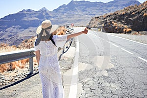 Hitchhiking woman travelling by hitchhike on road side, smiling happy on summer vacation