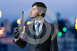 Hitman or assassin holds pistol with silencer in hand at dusk photo