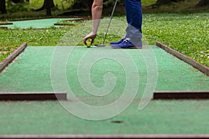 Hitting the ball on a mini golf course close up